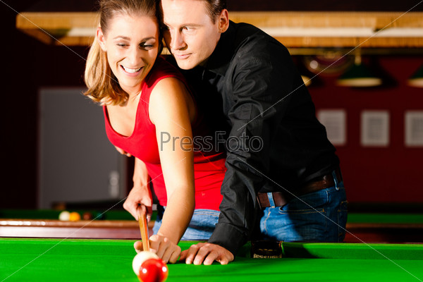 Couple (man and woman) in a billiard hall playing snooker, stock photo
