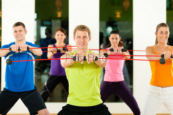 Group of five people exercising with a bar to strengthen the intrinsic muscles in gym or fitness club
