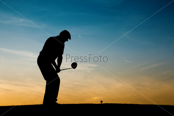 Senior man playing golf - pictured as a silhouette against an evening sky, stock photo