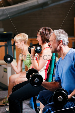 Senior people in a gym exercising with weights