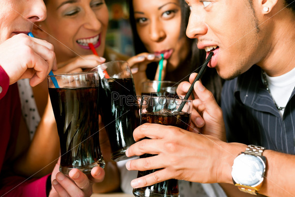 Four friends drinking soda in a bar with colorful straws