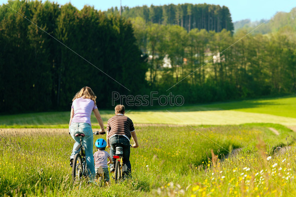 Family on a trip with their bicycles in a wonderful scenery, since their son is so young he is riding a training bike, stock photo