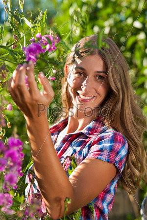 Happy woman in summer in garden with flowers on a wonderful day