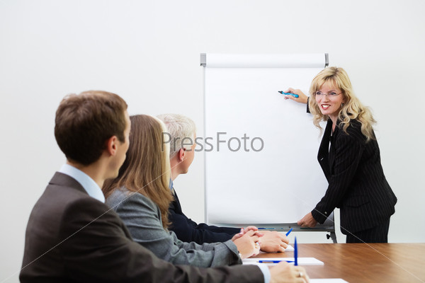 Businessteam listening to a coach giving a presentation on a flip chart (focus on coach)