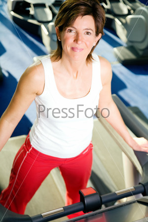 Woman on the treadmill, having a short break and looking around