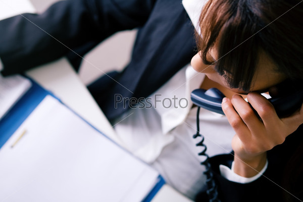 Girl in the office on the phone looking in a file, stock photo