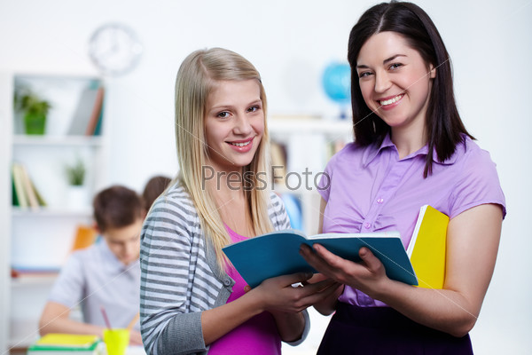 Happy teacher and her student looking at camera in college