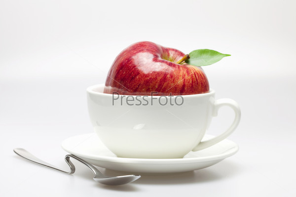apple in a cup and spoon isolated on white