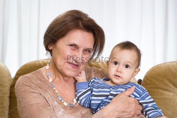 Пожилая женщина держит на руках маленького ребенка