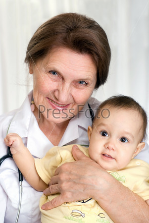 Пожилая женщина-врач держит на руках маленького ребенка
