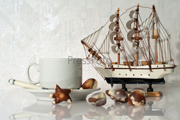 Still life with cup, candy, souvenir yacht and frame molding