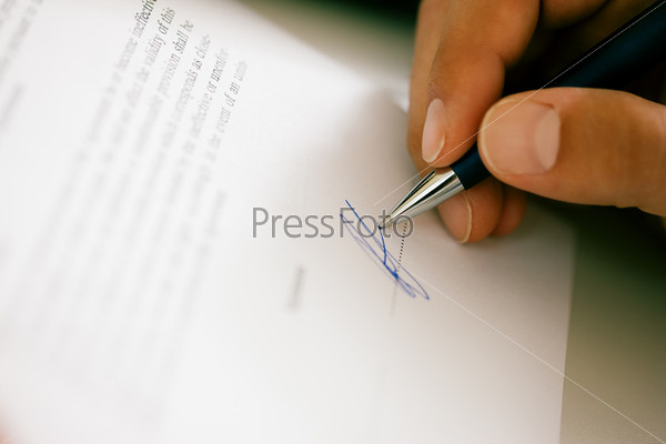 Man (only hand to be seen) signing a contract or another document (fake signature, focus on pen)