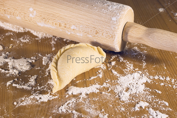 dumplings and a wooden rolling-pin on the table with flour