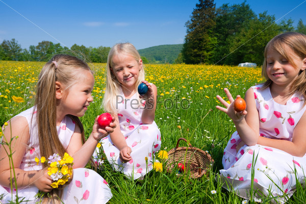 Children on an Easter Egg hunt on a meadow in spring