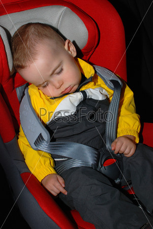 Годовалый мальчик спит в сиденье автомобиля