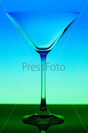 Conceptually illuminated martini glass on gradient background, stock photo