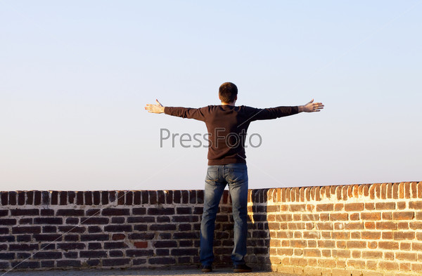 Мужчина с вытянутыми руками на фоне неба