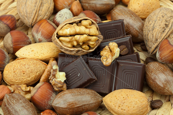 Bar of chocolate and nuts on a wicker mat, stock photo