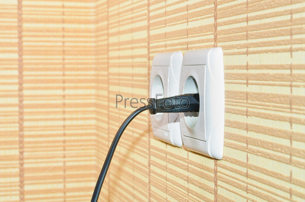 Power plug into the socket on the wall, stock photo