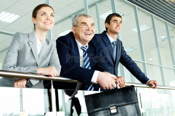 Three business people in office standing by banisters