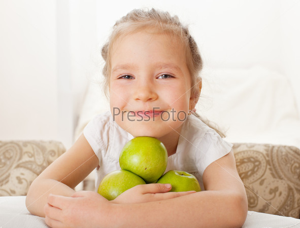 Child with apples. Little girl at home in the kitchen eating fruit