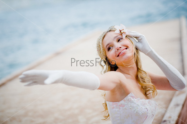 Beautiful happy bride with lilly in hair over sea