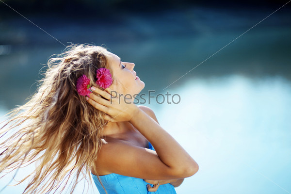 Portrait of young beautiful smiling female with flowers in her wet flying hair