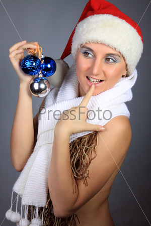 The young beautiful girl in a white cap and a white scarf with fur-tree toys. A studio portrait