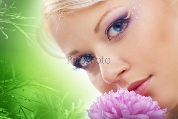 Cheerful young cute woman face with flower over natural green background, stock photo