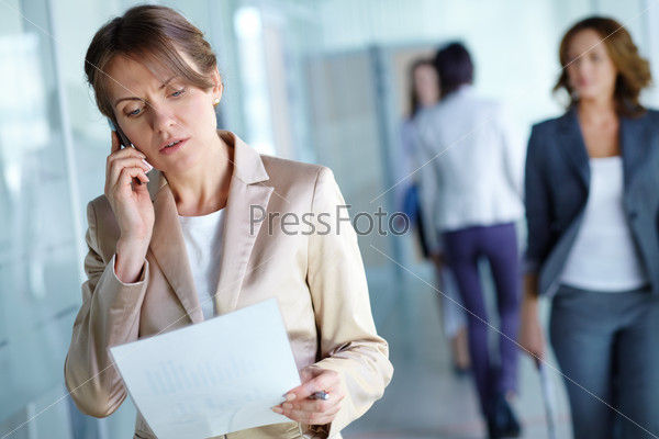Image of agent reading document while speaking on the phone in working environment