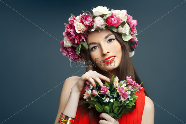 Portrait of beautiful smiling woman with a crown on his head and a bunch of flowers on a dark background in the studio. The concept of friendly spring.