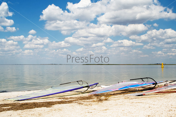 Surfboards on a beach a sea bay on background of the blue sky and clouds