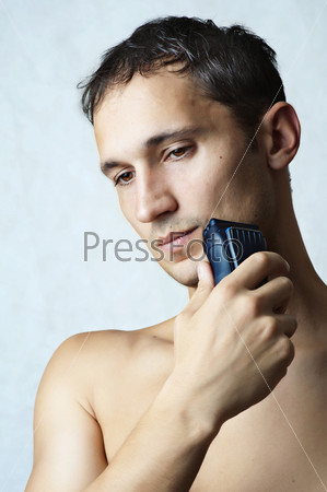 Fashion portrait of man shaved his chin by electric\
shaver