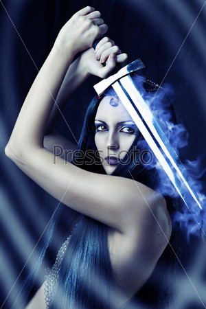 Young sexy woman warrior holding blue fire sword in hands with long healthy black hair.