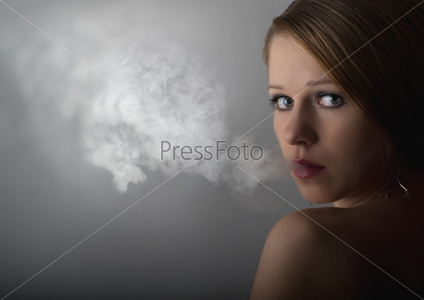 portrait of a beautiful young woman with cigarette smoke on a dark gray background