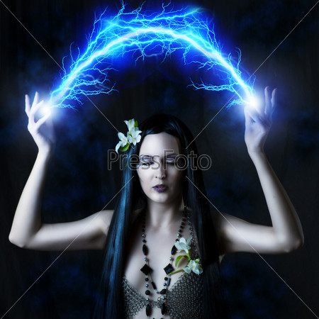 Fashion portrait of sexy woman - witch or elf. She is making magic - arc or flash lightning