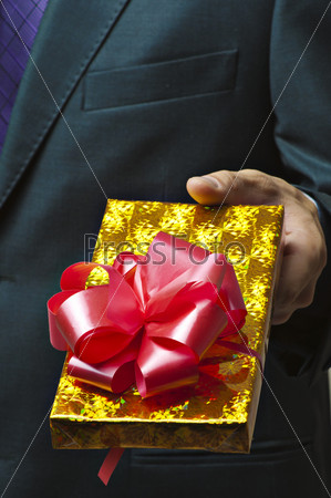 Male hands holding gift. Present in golden box with red ribbon