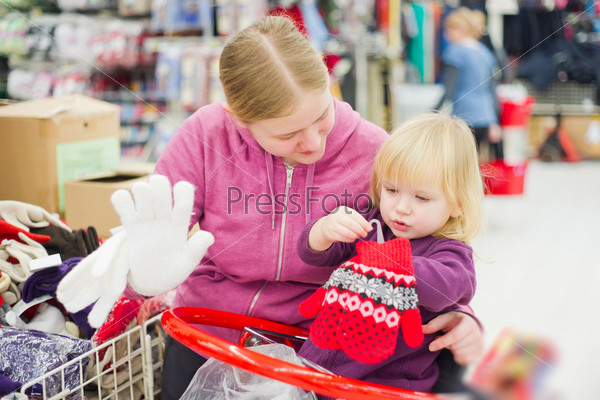 Mother and daughter look gloves in supermarket.