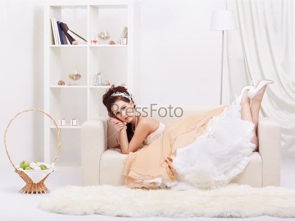 portrait of young beautiful retro woman in skirt with petticoat and corset lying on sofa in vintage flat
