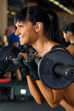 Beautiful woman is doing exercises with the bar  the sport club.