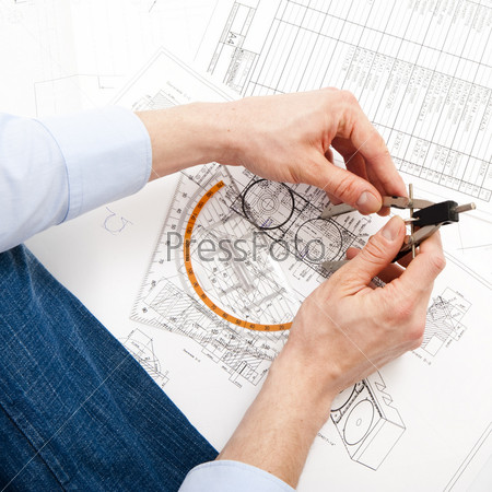 An engineer checking a technical drawing with a pair of compasses and a triangle