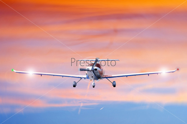 Approaching propeller aircraft seen from the front, against a vivid, radiant sky