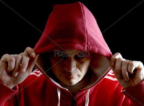 A grim looking Hoodlum lifting his hood with his right arm