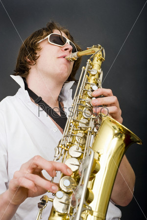 A man in a white shirt and open collar passionately playing the saxophone