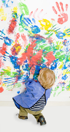 Young boy busy finger painting, kneeling down, to finish hsi work
