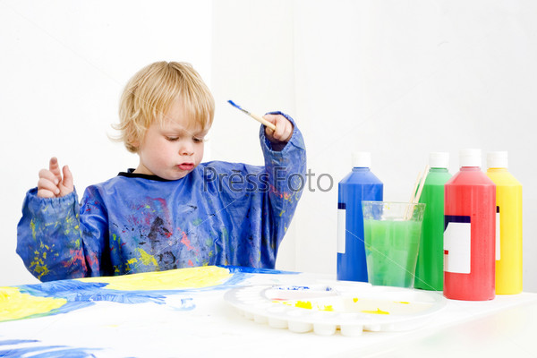 A young boy making a painting with poster paint