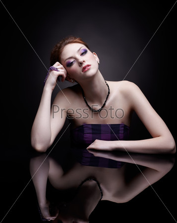 portrait of beautiful young red-haired woman at dark mirror table