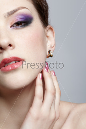 close-up half-face portrait of young beautiful woman touching her face with manicured fingers