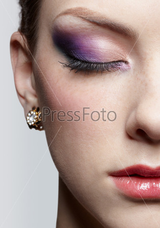 close-up half-face portrait of young beautiful woman with violet eye shadow closing eyes