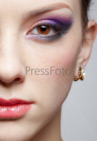 close-up half-face portrait of young beautiful woman with violet eye shadow